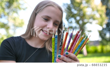 Group of multicolored pencils in young girl's hand. Group of multicolored pencils in young girl's hand. 66653235