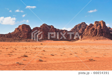 Red dusty desert with large rock massif and blue 66654391