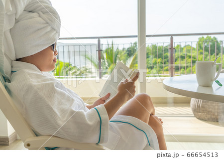 Side view of Asian woman relax on chair and reading book  66654513