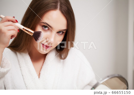 Beauty makeup, young woman with clean skin holds brush for applying makeup near her face 66655150