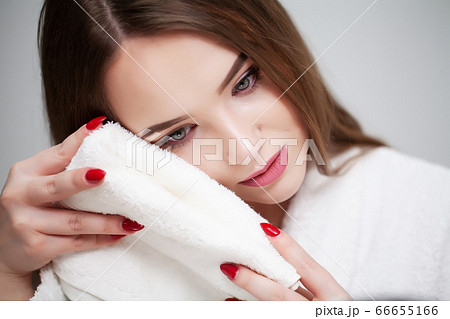 Cleansing facial skin, young woman holding white towel near facial skin after washing face 66655166