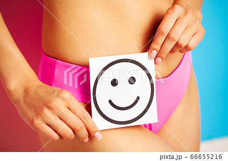 Stomach health and good digestion concepts, close up of healthy woman with beautiful fit slim body in pink panties holding card with happy smile in hands. 66655216
