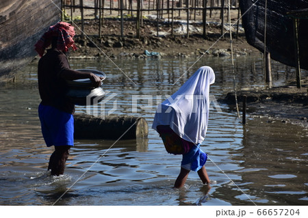 バングラデシュのコックスバザール　冠水した道路を歩くイスラム教徒の女学生と働く男性 66657204