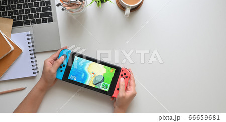 Woman playing Animal Crossing New Horizons on Nintendo Switch. 66659681