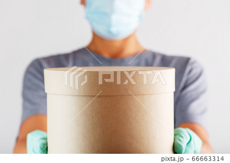 A delivery service courier in rubber gloves and a A delivery service courier in rubber gloves and a 66663314