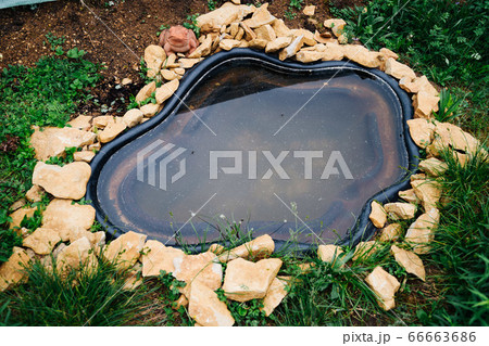 Beautiful pond in a backyard surrounded with stone during summer 66663686