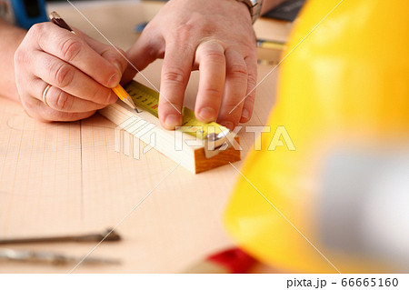 Arms of worker measuring wooden bar closeup Arms of worker measuring wooden bar closeup 66665160