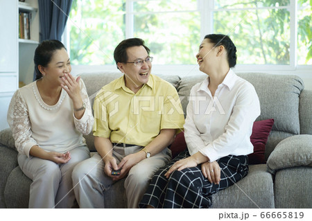 Asia group of friends sitting on couch, watching television and talking together, laughing and enjoying their time. Lifestyle and friendship concept. Asia group of friends sitting on couch, watching television and talking together, laughing and enjoying their time. Lifestyle and friendship concept. 66665819
