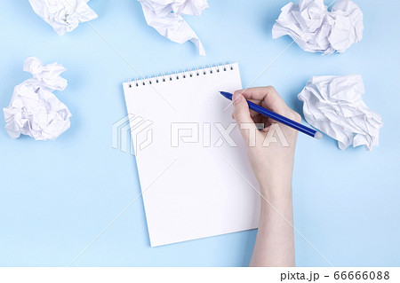 Woman writes in notebook around crumpled paper, Woman writes in notebook around crumpled paper, 66666088