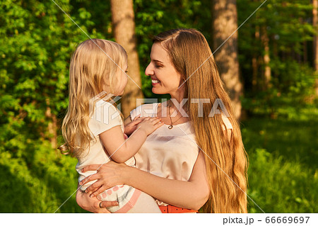 young woman affectionately looks at her little 66669697