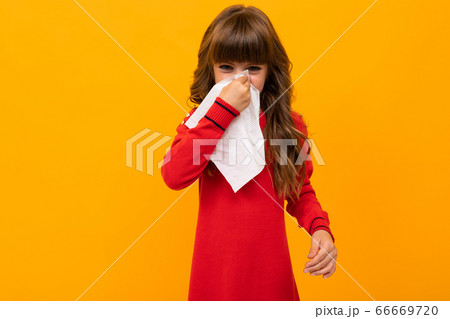 Beautiful little girl in dress plays with glasses isolated on yellow and orange background Beautiful little girl in dress plays with glasses isolated on yellow and orange background 66669720