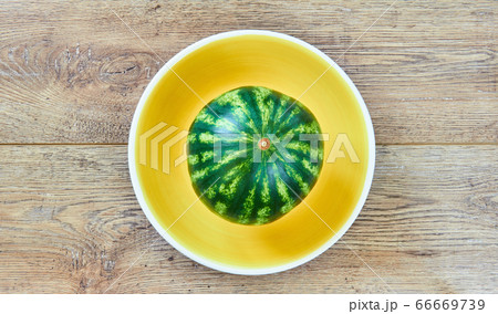 small watermelon on a yellow plate on a wooden 66669739