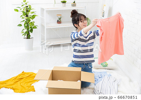 使わなくなった服をネットで売る準備をする女性 66670851