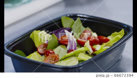 Chef preparing fresh salad for takeaway delivery order 66672394