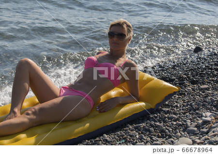 Happy woman smiling in sunglasses on an air mattress by the sea 66678964