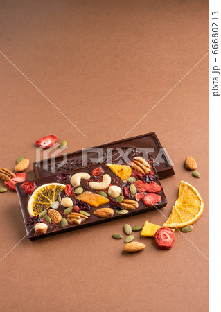 Chocolate dark Belgian bar with the addition of fruit nuts on brown background. Dessert food concept. Chocolate dark Belgian bar with the addition of fruit nuts on brown background. Dessert food concept. 66680213