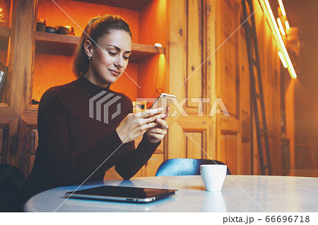 Beautiful woman posing while sitting with touch pad in modern coffee shop interior during work break Beautiful woman posing while sitting with touch pad in modern coffee shop interior during work break 66696718