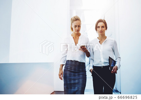 confident women entrepreneurs reading news by using digital tablet and cell telephone confident women entrepreneurs reading news by using digital tablet and cell telephone 66696825