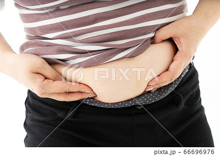 お腹の脂肪をつまむ中年女性の写真素材