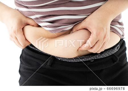 お腹の脂肪をつまむ中年女性の写真素材