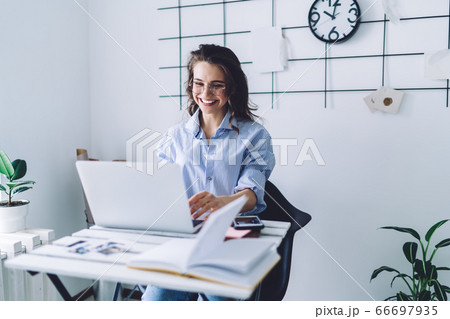 Happy woman working at laptop while sitting at desk Happy woman working at laptop while sitting at desk 66697935