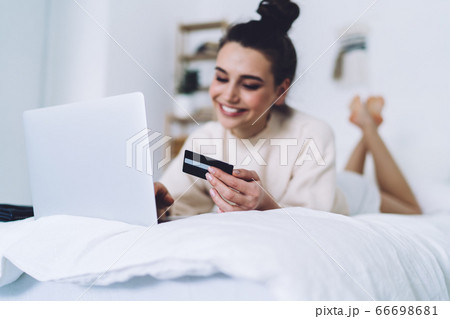 Cheerful brunette purchasing online using laptop at home 66698681