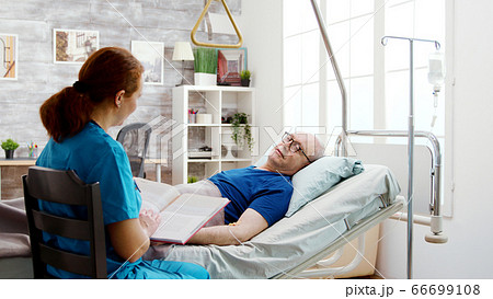 Old retired sick man lying in hospital bed in a nursing home 66699108