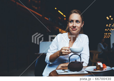 Cheerful female posing with cup of coffee in hand while relax in comfortable restaurant Cheerful female posing with cup of coffee in hand while relax in comfortable restaurant 66700430