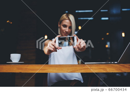 Close up of mobile phone lying on a wooden table near cup of cappuccino Close up of mobile phone lying on a wooden table near cup of cappuccino 66700434