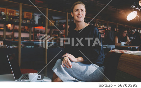 Beautiful female keyboarding on portable net-book while relaxing in coffee shop during free time 66700595