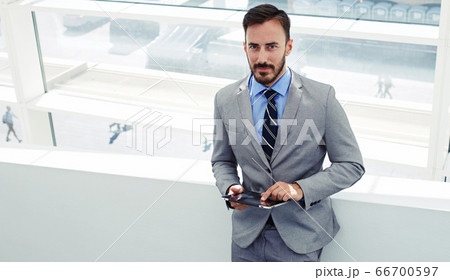 Half length portrait of rich businessman holding portable digital tablet during work break in hallway Half length portrait of rich businessman holding portable digital tablet during work break in hallway 66700597