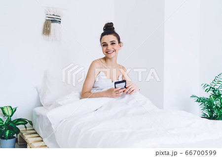 Glad woman chilling on bed in morning at home Glad woman chilling on bed in morning at home 66700599