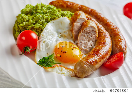 Pork sausages, egg, green pea on a white plate Pork sausages, egg, green pea on a white plate 66705304