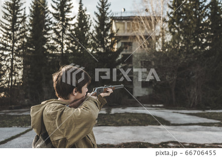 The boy aim through the scope. A man with a gun in a protective jacket is standing 66706455