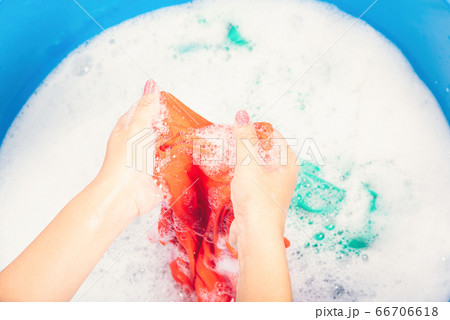Woman use hands washing color clothes in basin 66706618