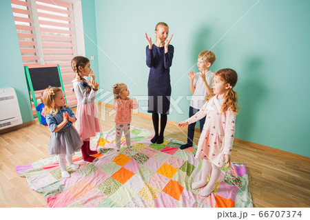 Female teacher and preschool pupils having fun together. Female teacher and preschool pupils having fun together. 66707374