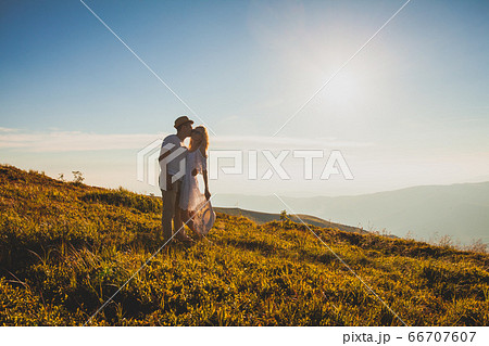 Embracing romantic couple in white on a hill 66707607
