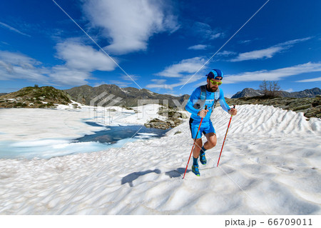 Skyrunner man uphill in a snowy stretch 66709011