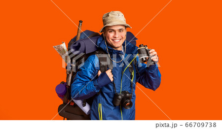 Hiker with binoculars smiling over orange background Hiker with binoculars smiling over orange background 66709738