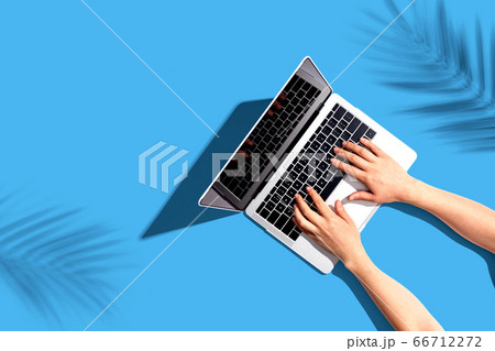 Person using a laptop computer with tropical plant shadow Person using a laptop computer with tropical plant shadow 66712272