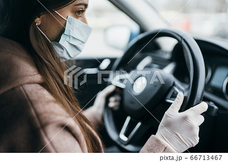 Young woman in a mask and gloves driving a car. Young woman in a mask and gloves driving a car. 66713467