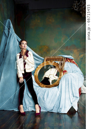 beauty rich brunette woman in luxury interior near empty golden frames, lifestyle people concept 66715455