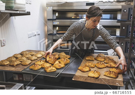 A baker loading baked seeded buns on a tray. A baker loading baked seeded buns on a tray. 66716555