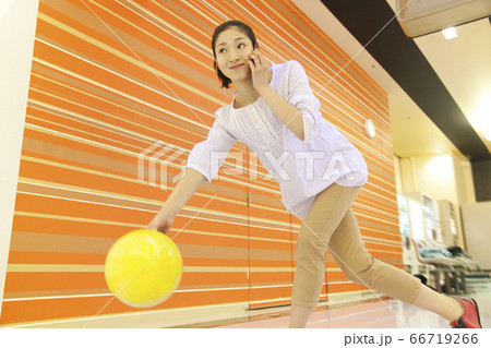 ボウリングをしながら電話する女性 66719266