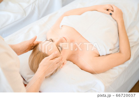 Beautiful woman receiving head and facial massage in spa salon Beautiful woman receiving head and facial massage in spa salon 66720037