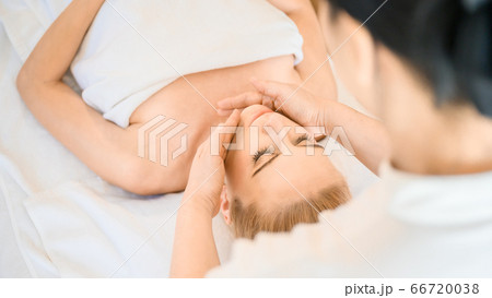 Beautiful woman receiving head and facial massage in spa salon Beautiful woman receiving head and facial massage in spa salon 66720038
