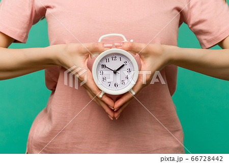 Woman holding alarm clock in hand on blue 66728442