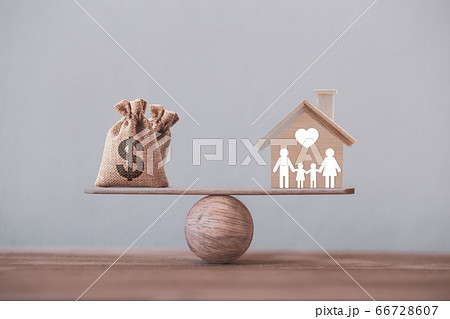 House mortgage and family financial management concept: Wooden home and heart, Family member and US dollar hessian bags on balance scale. Prepare expenses for the purchase of a residence. 66728607