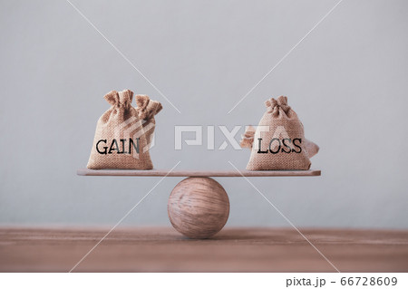Gain and loss bags on a basic balance scale on blackboard. Capital investment gain and loss, financial concept, depicts balancing between profit and loss while managing assets e.g bonds, stocks, deriv 66728609