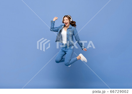 Happy young Asian woman jumping and listening to music 66729002